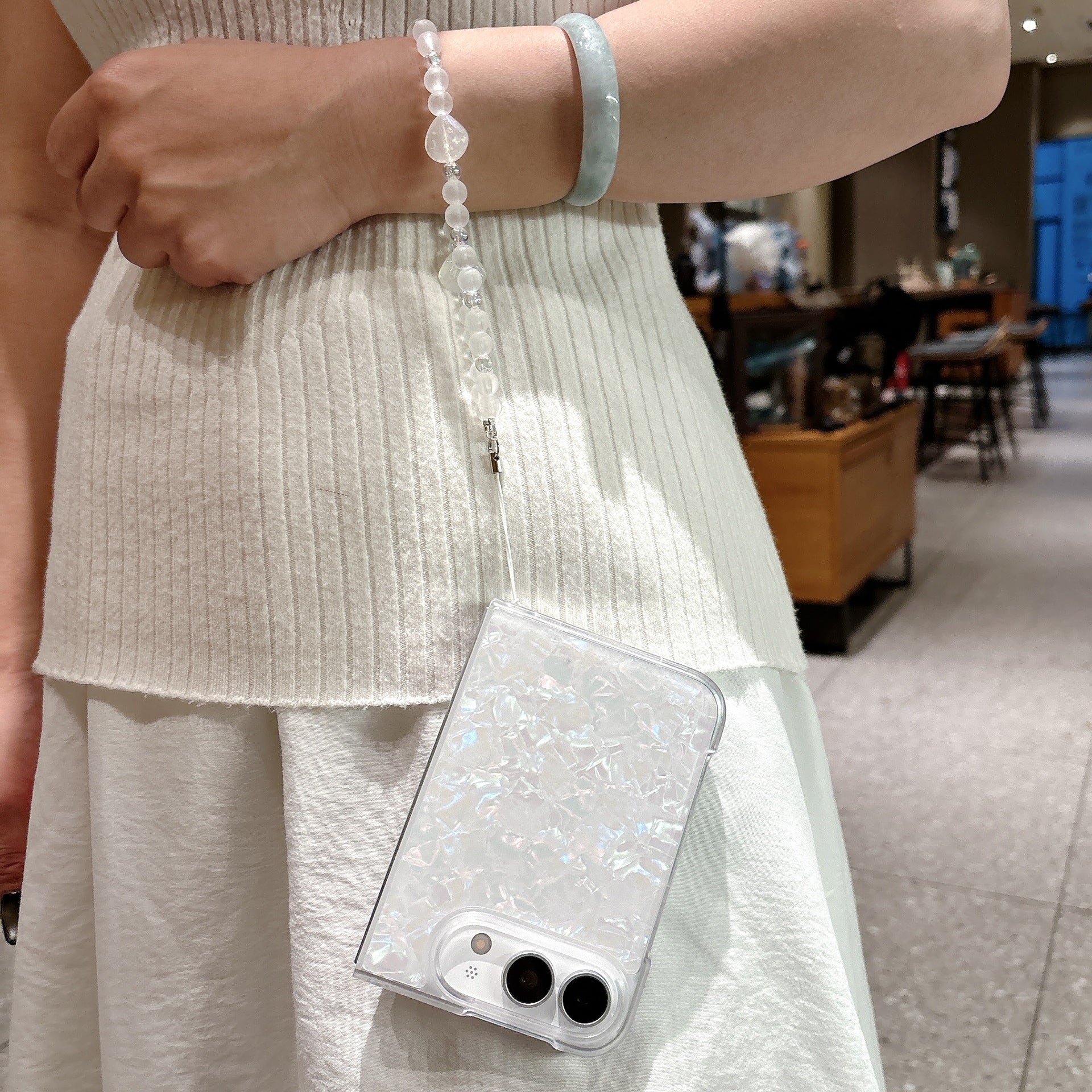 iPhone Duo pearl shell case worn with beaded wrist strap as a fashion accessory
