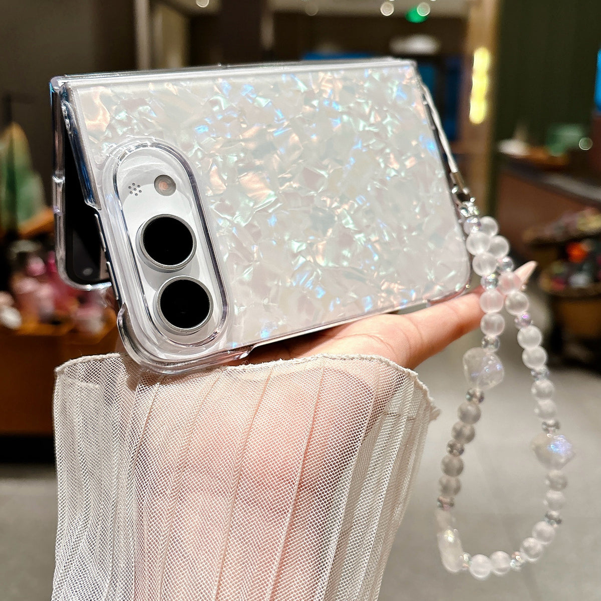 Side view of iPhone Duo pearl shell case with iridescent finish and wrist strap